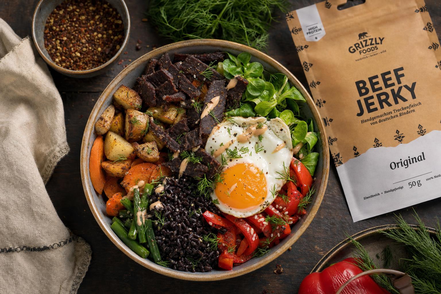 Bunte Bowl mit schwarzem Reis, Röstkartoffeln, Gemüse, knusprigem Rindfleisch-Jerky und Spiegelei, garniert mit frischen Kräutern.