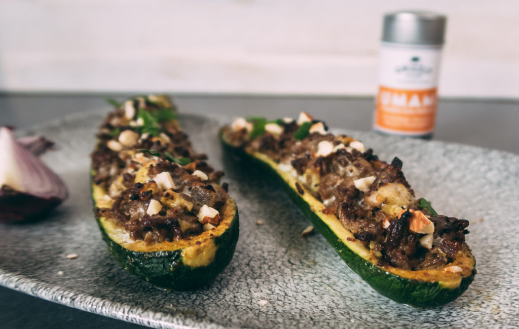 Auf einem Teller von Churchill liegen gefüllte Zucchini mit Hackfleisch. Im Hintergrund ist eine Dose UMAMI-Gewürzmischung von Grizzly Spices zu sehen.