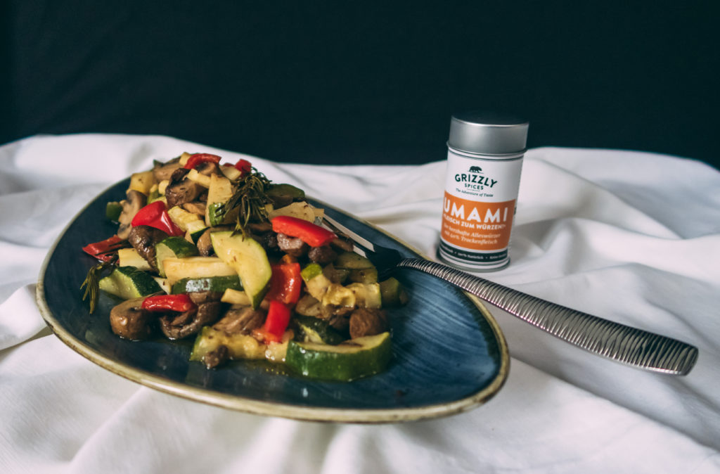 Auf einem Teller von Churchill ist unser Ofengemüse mit UMAMI zu sehen. Im Hintergrund steht eine Dose UMAMI-Gewürzmischung.