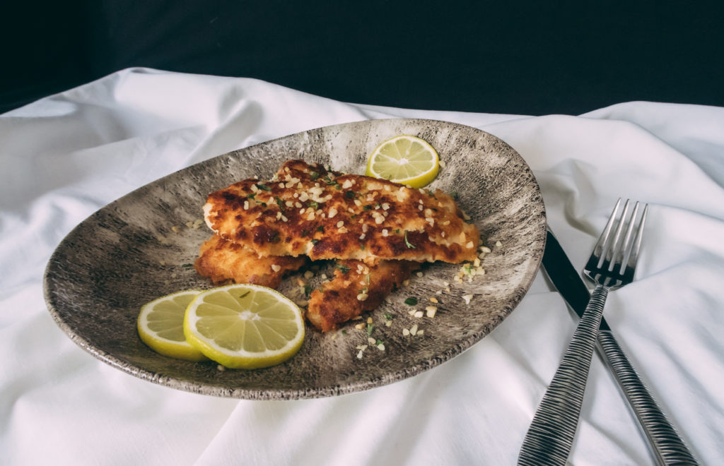 Auf einem Teller von Churchill liegt der Kokosfisch. Dekoriert wurde mit Zitronenscheiben und etwas Petersilie.