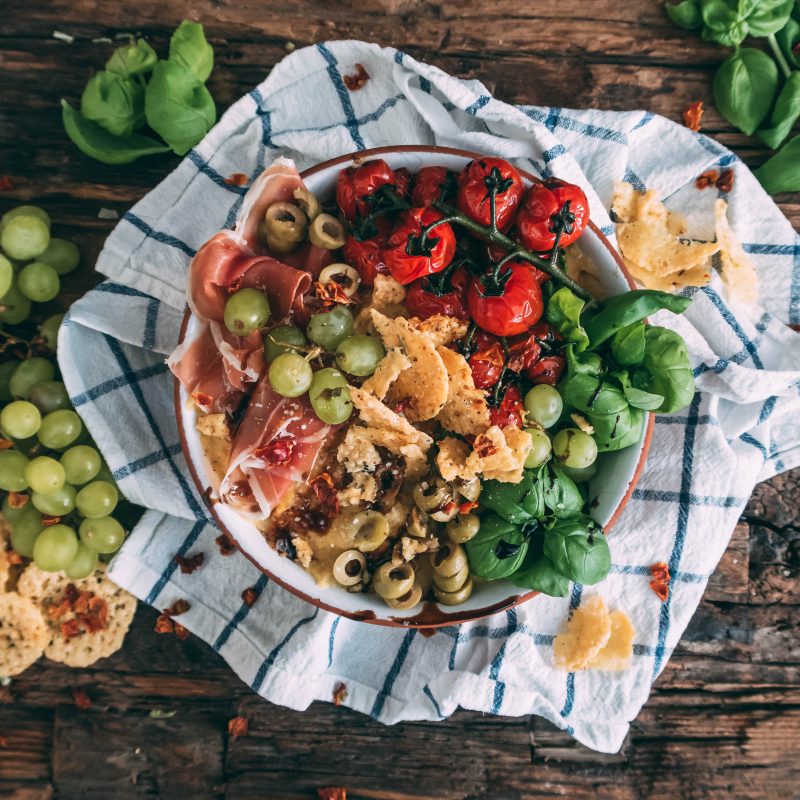 Polenta Bowl mit Käsechips, Tomaten, Trauben und Gemüsebrühe