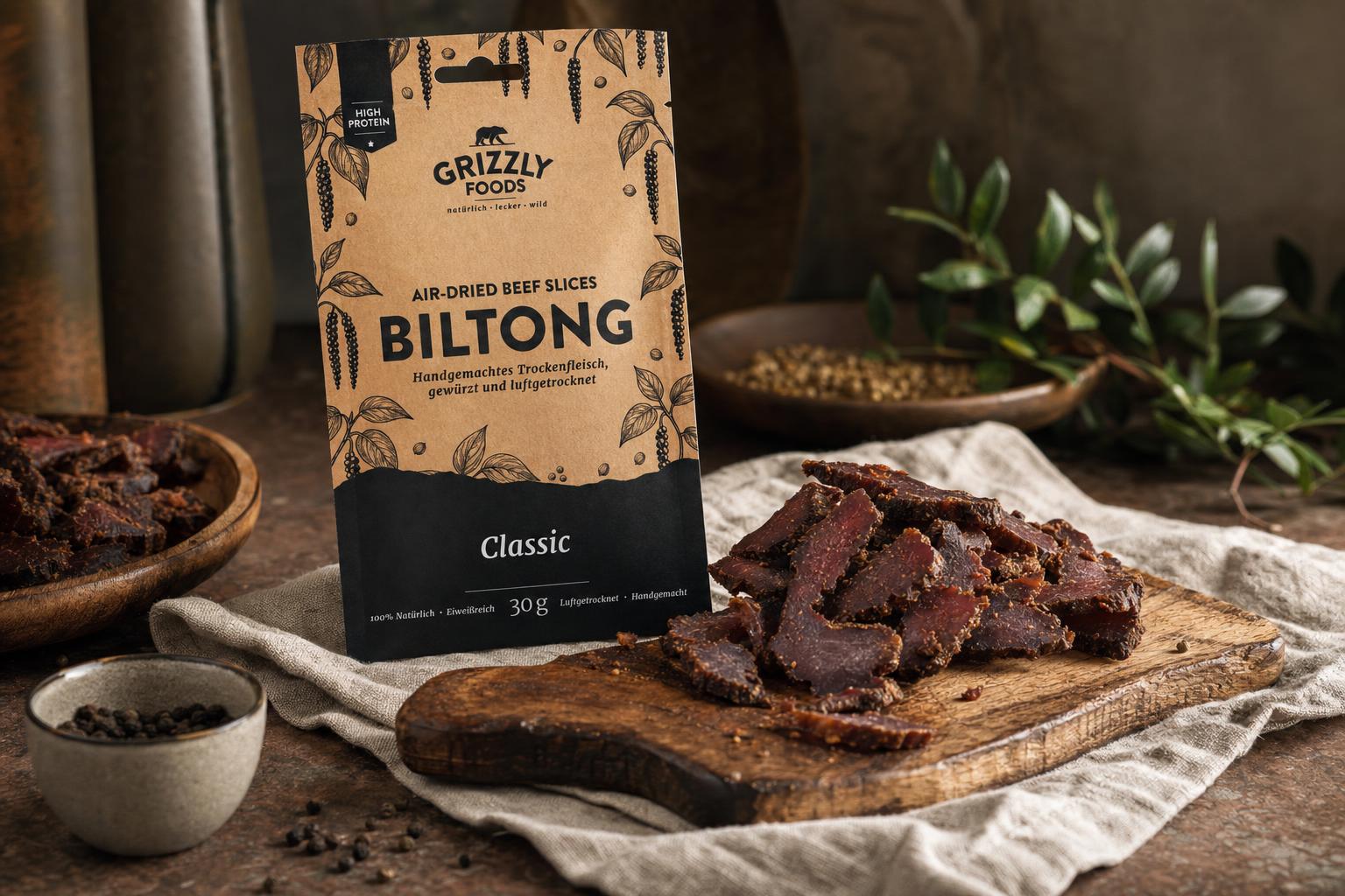 Biltong – Getrocknete Rindfleischstreifen auf einem rustikalen Holzbrett neben einer Verpackung, stimmungsvoll angerichtet als Snack.