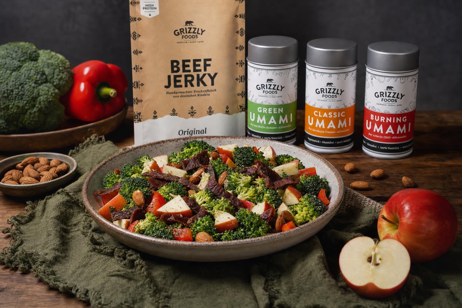 Brokkoli-Apfel-Salat mit Paprika, Mandeln, Beef Jerky und Dressing auf einem weißen Teller angerichtet