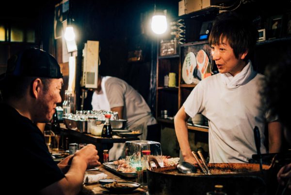 Zwei Personen, die sich an einem Streetfood Stand, an dem japanisch gegrillt wird, unterhalten