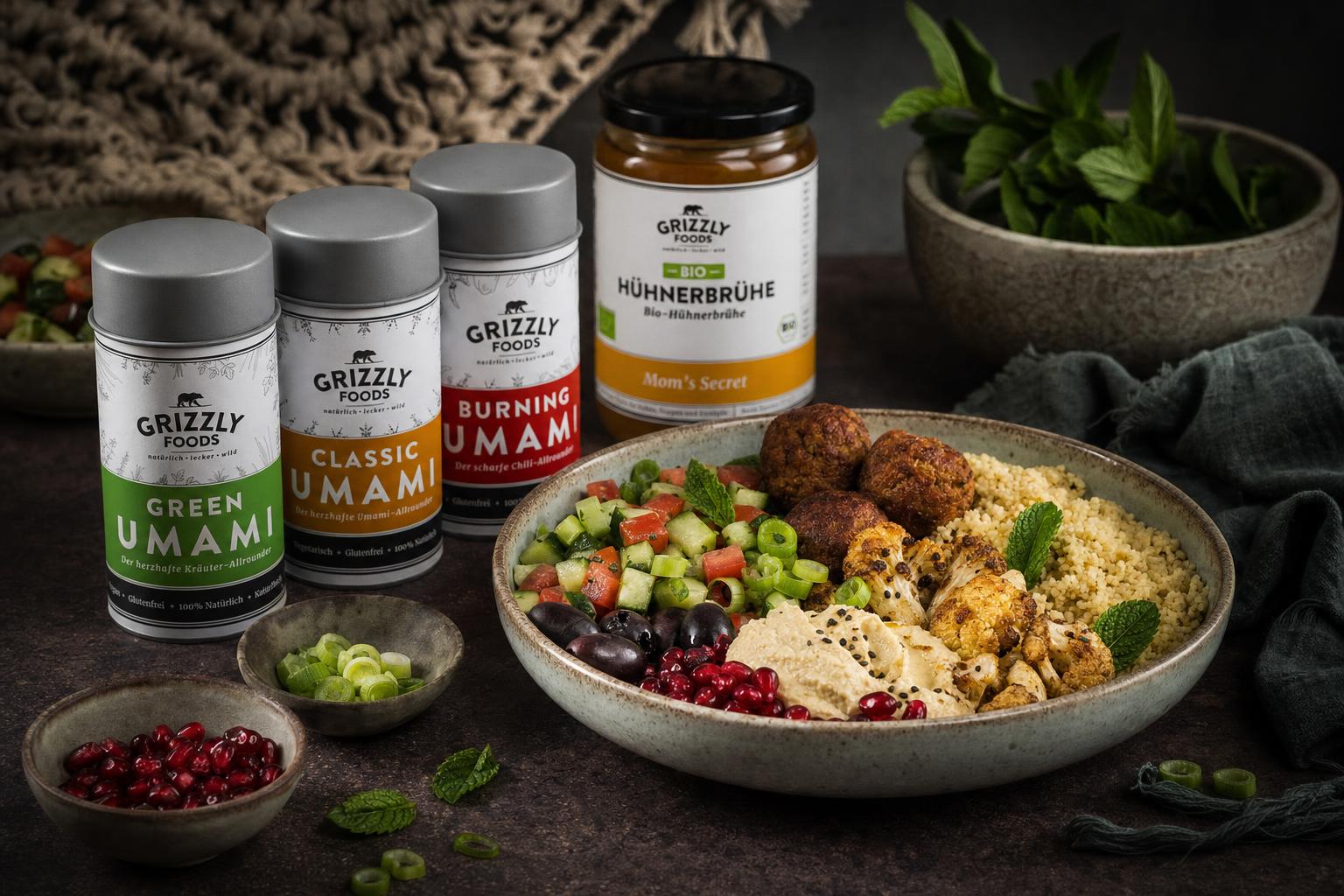 Bunte Levante Bowl mit Falafel, Couscous, geröstetem Blumenkohl, Hummus, Granatapfelkernen, Oliven, Salat und Joghurt-Dip