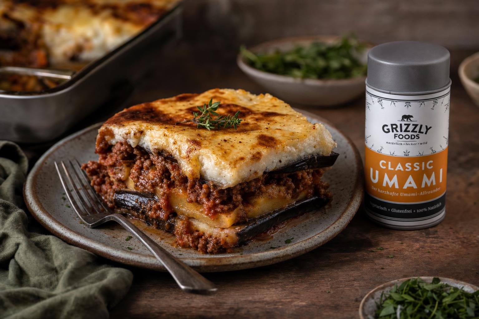 Eine Portion Moussaka mit goldbrauner Kruste, serviert auf einem Teller, daneben ein Glas mit Gewürzmischung.