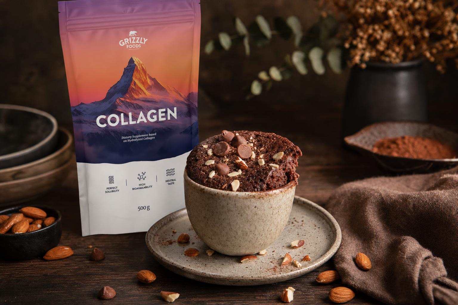 Kleiner Schoko-Mug-Cake mit Schokostückchen und Mandeln, angeschnitten, auf dunklem Brett, daneben verstreute Mandeln und Schokolade.